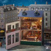 A detailed wooden dollhouse kit of a pink princess villa with built-in LED lights displayed in a miniature street setting.