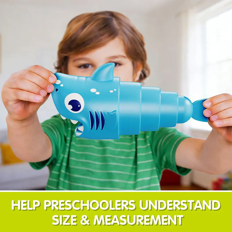A child is holding a blue plastic shark toy for educational purposes.