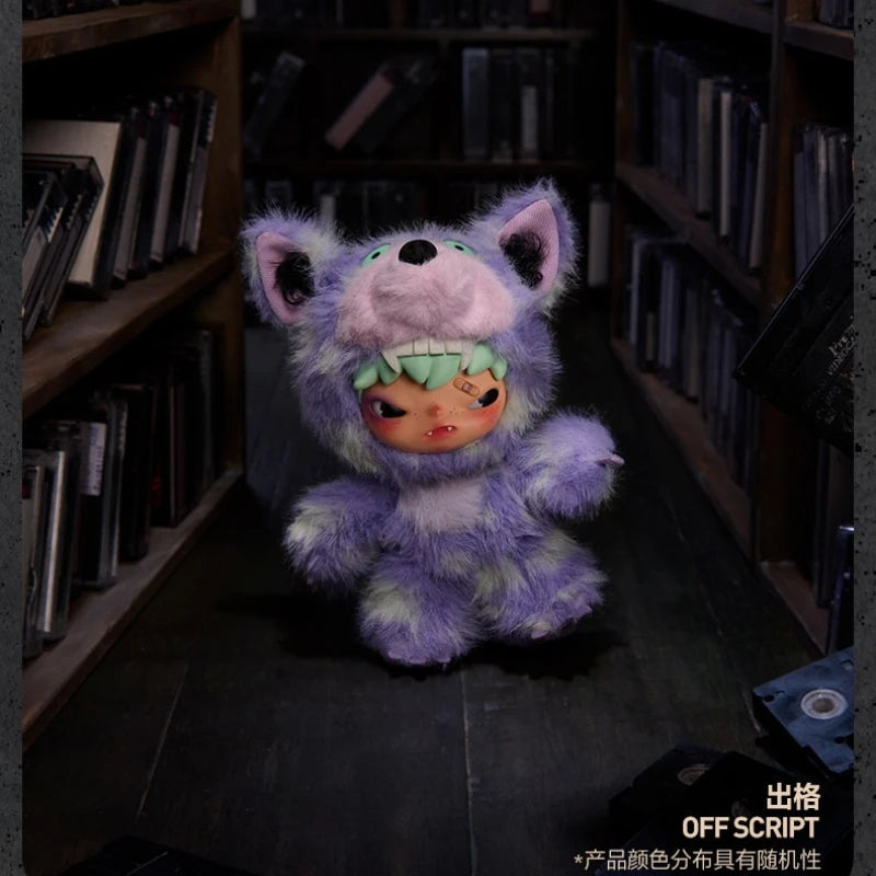A purple and green plush doll pendant featuring an animal face in a dimly lit bookshelf setting.