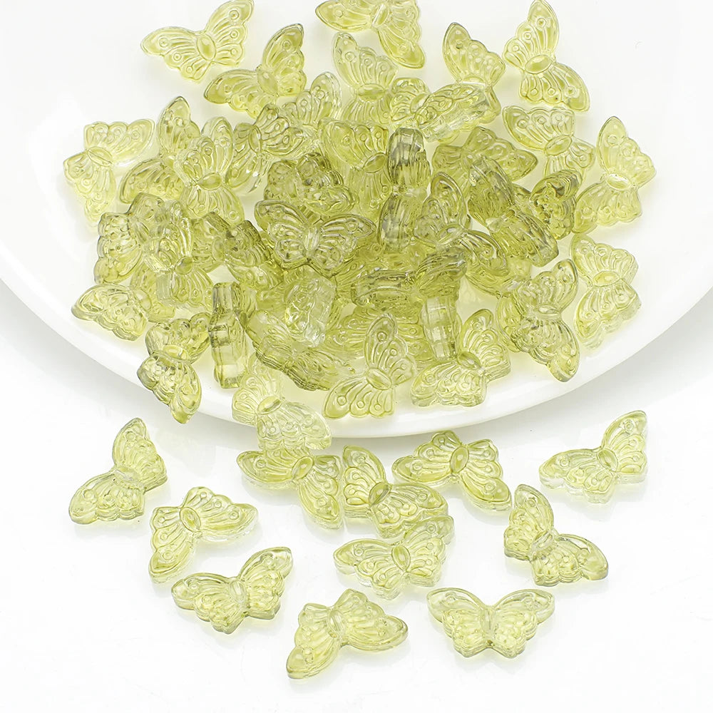 A pile of light green glass butterfly beads for jewelry making