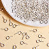A pile of silver metal eye pins for jewelry making and DIY crafts scattered on a light background.
