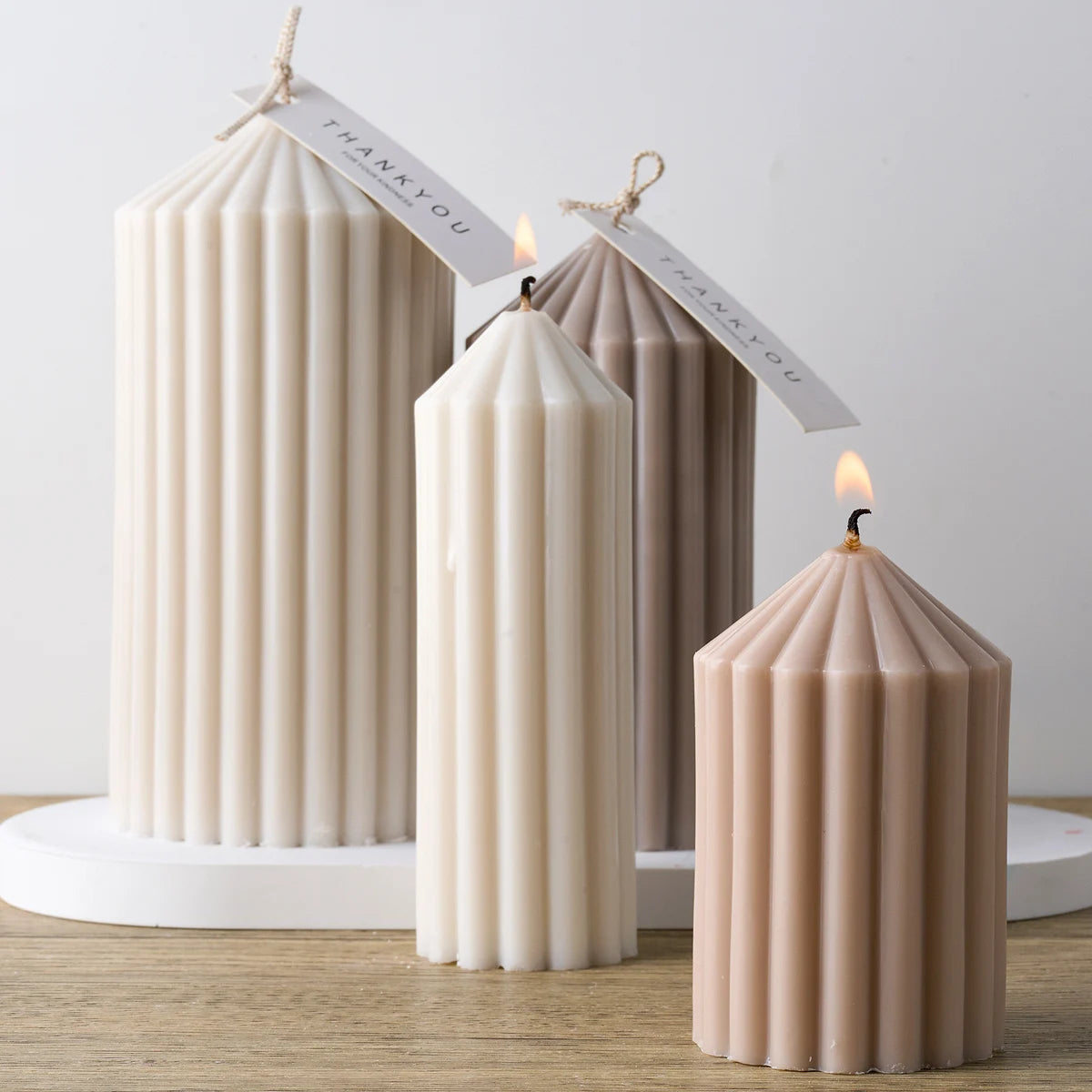 Three decorative silicone candles in cream and taupe colors with thank you tags