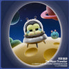 A collectible figurine of a crying baby in a silver helmet floating in space against a dark blue and purple starry background