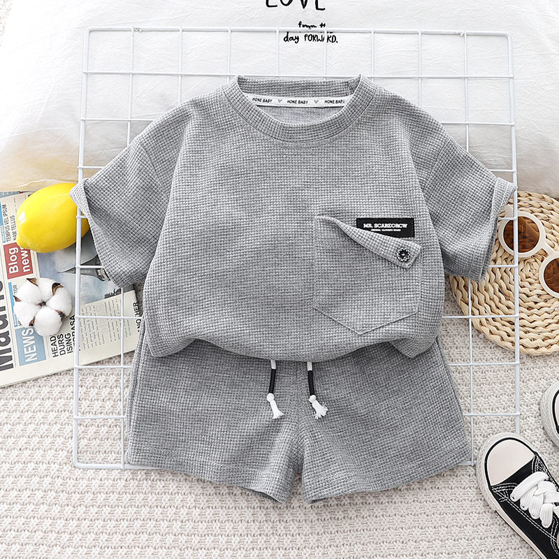 A gray boys' summer cotton t-shirt and shorts set laid out on a white grid background.