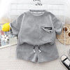 A gray boys' summer cotton t-shirt and shorts set laid out on a white grid background.