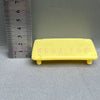 Yellow rectangular plastic toy with molded letters MGOATOY placed next to a ruler.