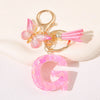 Gold initial heart keychain featuring a pink butterfly charm and a pink letter G pendant