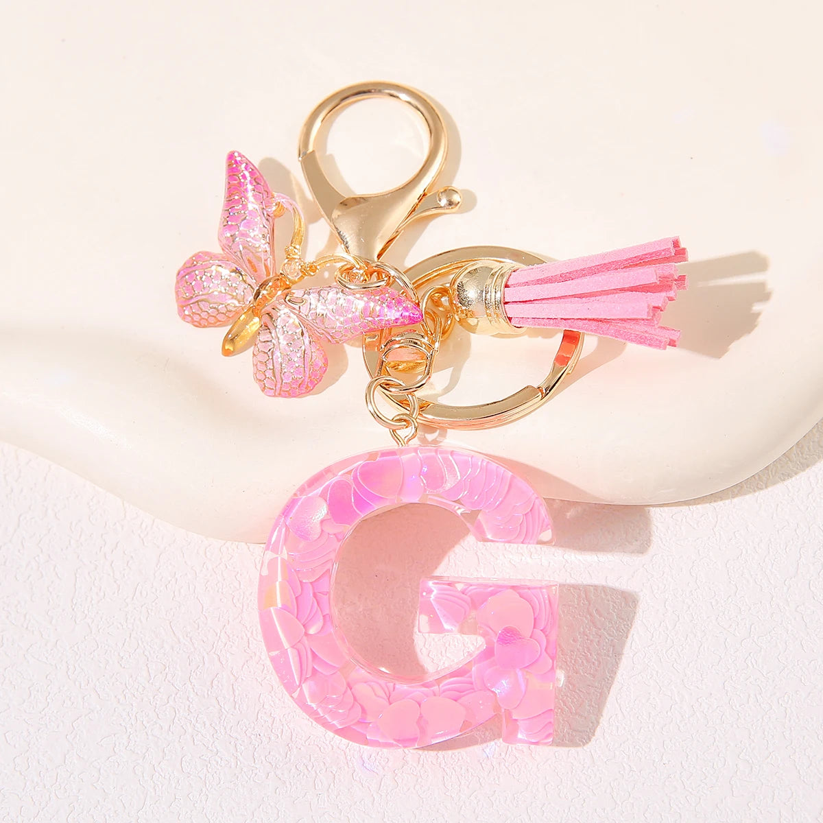 Gold initial heart keychain featuring a pink butterfly charm and a pink letter G pendant