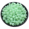 A pile of translucent light green acrylic round beads for jewelry making in a black bowl.