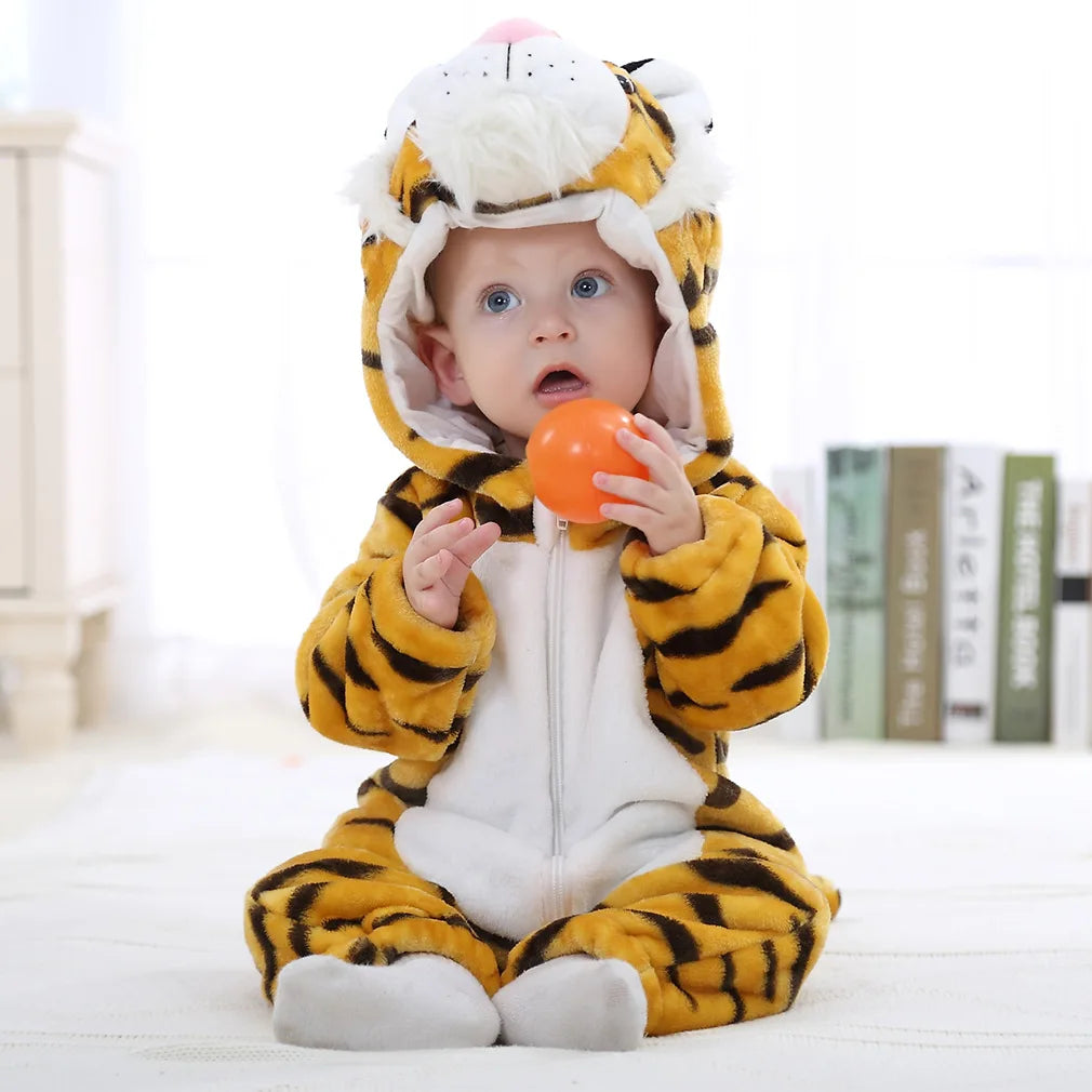 A baby wearing an adorable animal hooded romper with yellow and black stripes, sitting on a white surface.