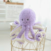A purple octopus plush toy with white tentacles hanging from a gold wire stand.