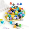 A collection of colorful rhinestone acrylic beads in various shades and sizes arranged on a light yellow plate.