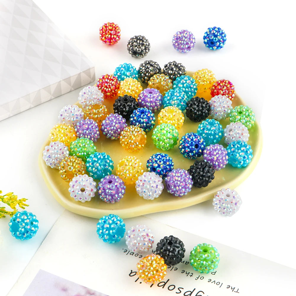 A collection of colorful rhinestone acrylic beads in various shades and sizes arranged on a light yellow plate.