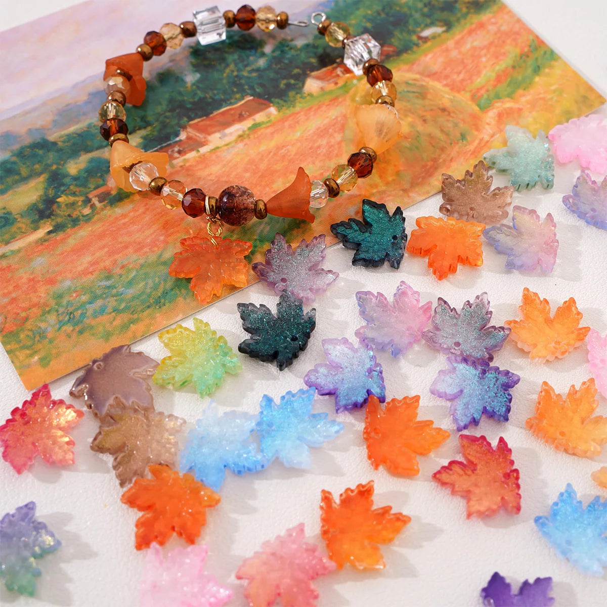 A string of amber and brown glass beads shaped like maple leaves is displayed on a piece of paper.