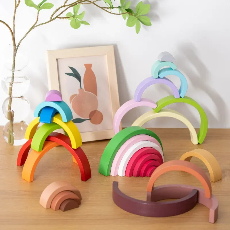 Collection de blocs arc-en-ciel en bois colorés empilables, disposés sur une surface en bois.