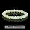 A bracelet of light green natural mountain jade beads displayed on a reflective surface.