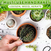 A hand holds a black multi-use hand rake tool used for loosening, weeding, and aerating soil in potted plants.