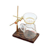 A miniature hand-brewed coffee stand set for dollhouse featuring a glass carafe and brass accessories on a wooden base.