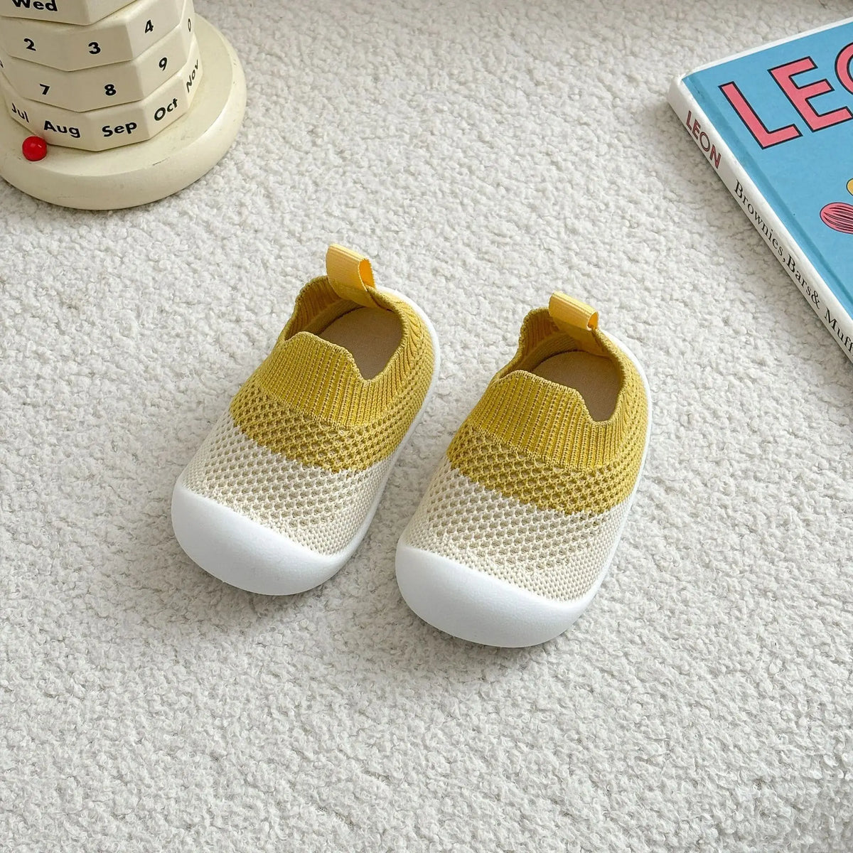 A pair of yellow and white breathable anti-slip baby first walker shoes resting on a white surface.
