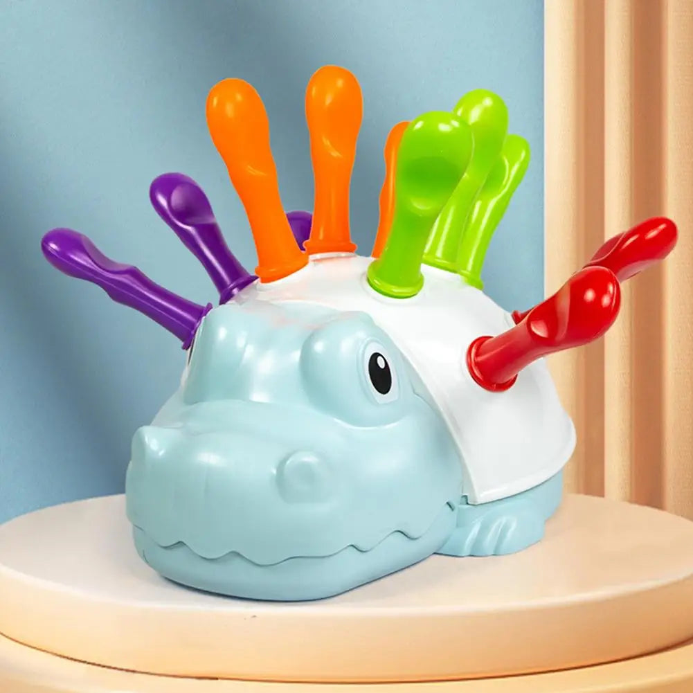 A white and blue hedgehog toy with colorful orange, purple, and green pegs for fine motor skill practice.