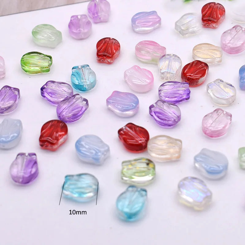 A collection of gradient tulip glass beads in various shades of purple, pink, and red are displayed on a white surface.