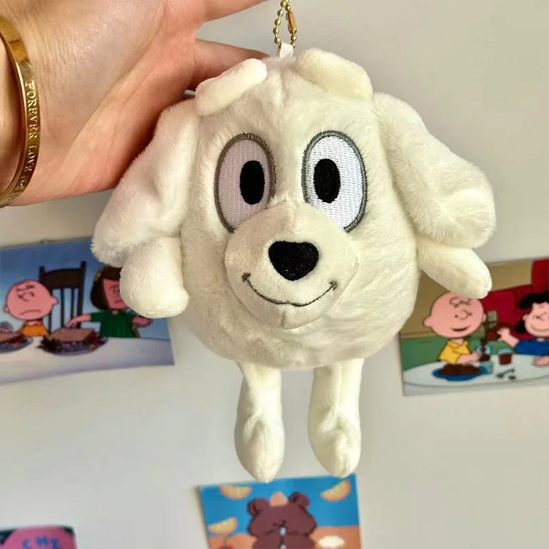 A white plush dog toy resembling a Golden Retriever, hanging from a gold chain.