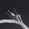 A close-up view of silver-plated classical guitar strings with transparent nylon cores against a dark background.