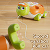 An orange and green pull car toy is shown with a separate green phone attachment on a wooden surface.