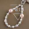 A necklace featuring pink and white pearls and crystal stars attached to a silver charm with a bag clip.