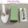 A set of green and white beach sand castle building tools including a shovel and a mold