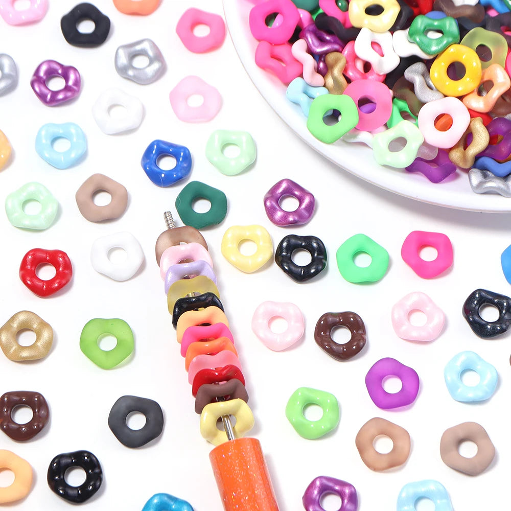 Assortment of colorful acrylic spacer beads in various shapes and colors scattered on a white surface.