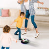 A woman is holding a floating soccer ball with LED lights and music while a child plays nearby.