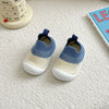 A pair of blue and cream knitted baby first walker shoes resting on a white textured surface.
