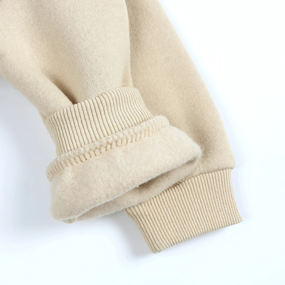 A close-up of a beige knit sleeve and cuff from a kids' multicolor pullover hoodie.