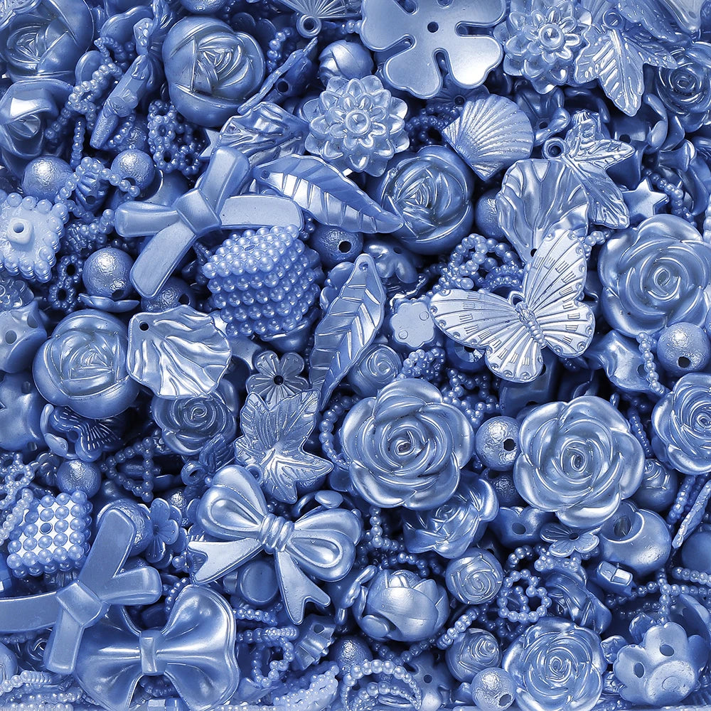 A close-up of blue iridescent butterfly shell acrylic beads and various silver-toned jewelry components for DIY crafting.