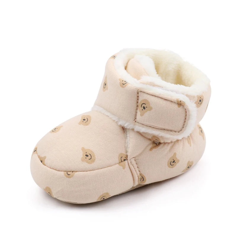 A pair of light beige baby winter snow boots with fuzzy ball accents and a sherpa lining.