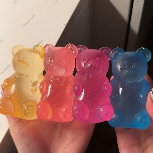 Une main tient un set de jouets anti-stress en gélatine colorés, jaune, rose et bleu.