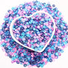 A heart-shaped mound of colorful polymer clay sprinkles in shades of purple, blue, and pink.