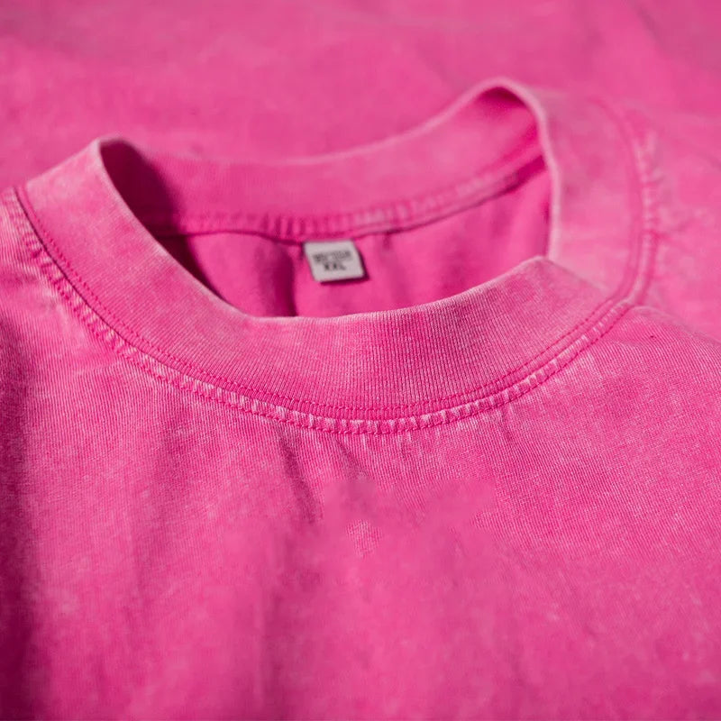 A close-up of a bright pink men's retro washed heavyweight cotton t-shirt with a crew neck collar.