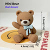 A dark brown Mini Bear teddy bear figure standing on a cake base.
