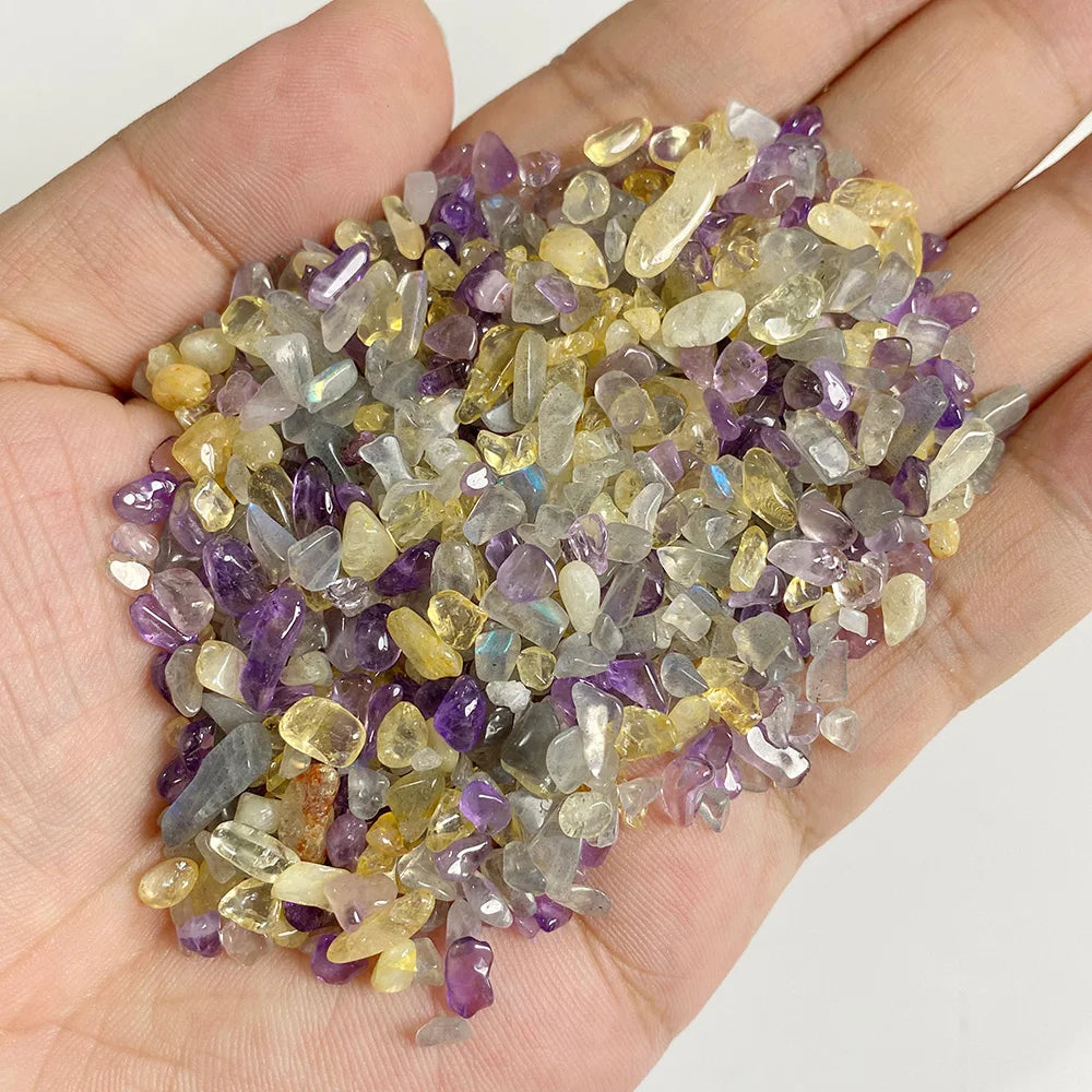A handful of natural tumbled stone chips in shades of purple, yellow, and clear quartz crystals.