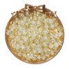 A round gold-toned dish filled with clear glass crackle beads for jewelry making.