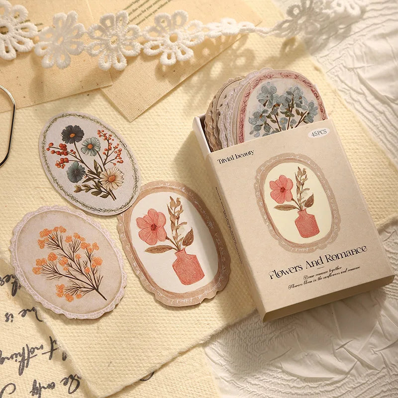 A box of vintage floral stickers with 45 sheets for scrapbooking and journaling displayed on a light fabric.