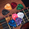 A collection of guitar accessories including a capo, tuner, and picks arranged on a wooden surface.