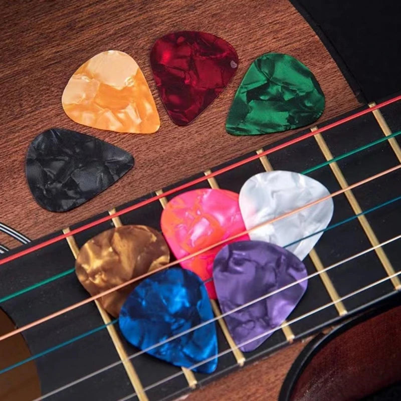 A collection of guitar accessories including a capo, tuner, and picks arranged on a wooden surface.