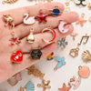 A hand holds a variety of assorted metal pendants and charms for jewelry making.