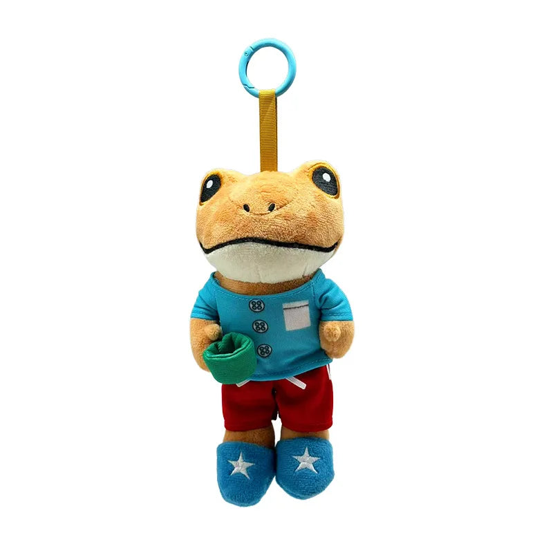 A cute plush frog doll with a light brown body, blue accents, and a yellow hanging loop.