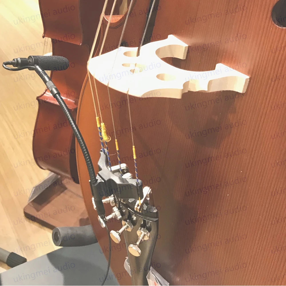 A white clip-on condenser microphone with a gooseneck is mounted on a wooden instrument case.