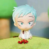 A light blue anime-style mini figure with spiky hair and bright green eyes sitting on a green surface.