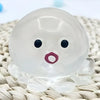 A clear, squishy ocean octopus fidget toy with black eyes and a pink mouth resting on a woven surface.